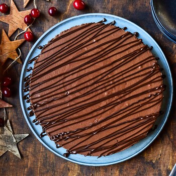 Une tarte au chocolat et aux épices entourée de décorations de Noël. 