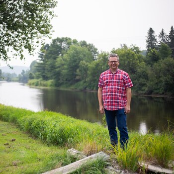 Un homme se tient debout près d'une rivière.