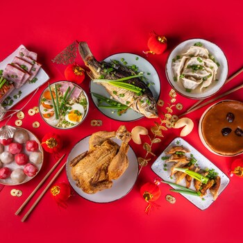Des plats de poisson, de dumplings, de poulet, de desserts et d'accompagnement sur une table.