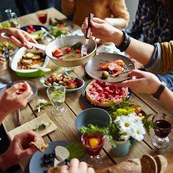 Des gens partagent à table un repas composé de plusieurs petits plats.