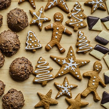 Biscuits de Noël de différentes tailles, formes et saveurs sur un plan de travail en bois.