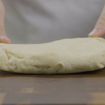 Un bloc de pâte est posé sur une planche à découper. 