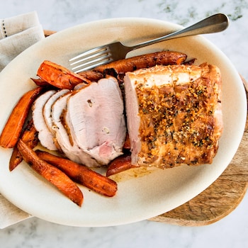 Un rôti de porc dans une assiette avec des carottes rôties.