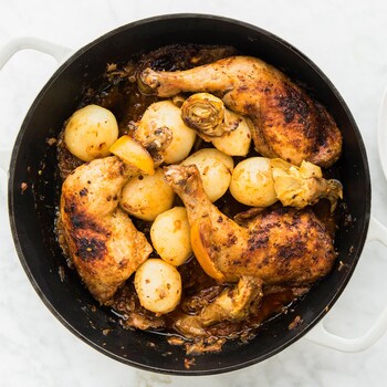 Une casserole remplie de cuisses de poulet, d'olives et d'artichauts et une assiette prête à être servie.