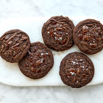 Cinq biscuits double chocolat dans une assiette.