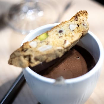Un biscotti aux trois noix placé sur le dessus d'une tasse de chocolat chaud.