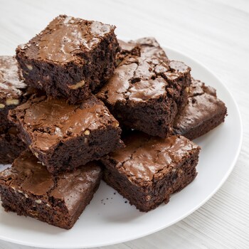 Des carrés de brownies disposés en pyramide dans une assiette.