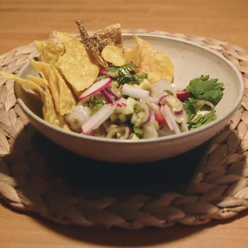 Un bol garni de ceviche, radis, coriandre et de croustilles de maïs.