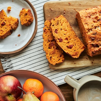 Un pain au cheddar et au chorizo est coupé en tranches sur une planche à découper en bois. 