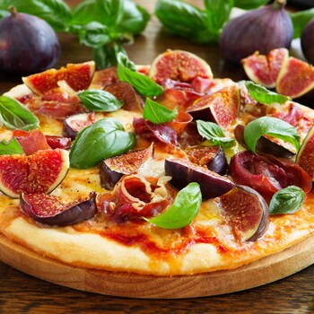 Une pizza recouverte de figues, de basilic, de fromage et de prosciutto.