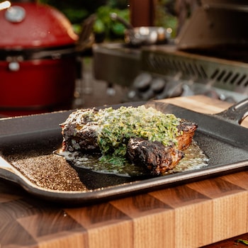Un steak grillé au BBQ servi avec du beurre aux herbes.