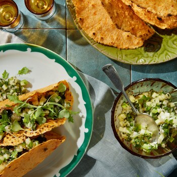 Sur une table, il y a une assiette avec des tacos à la salsa de pommes et jalapeno, ainsi qu'un petit bol de salsa.