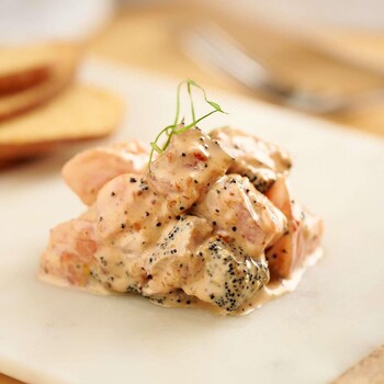 Du tartare de thon et de saumon au miso et aux pacanes servi dans une assiette avec des croûtons.