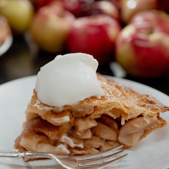 Une pointe de tarte aux pommes garnie d'une boule de crème glacée à la vanille.