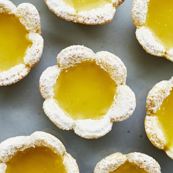 Des petites tartelettes au citron en forme de coeur sont déposées sur un comptoir.