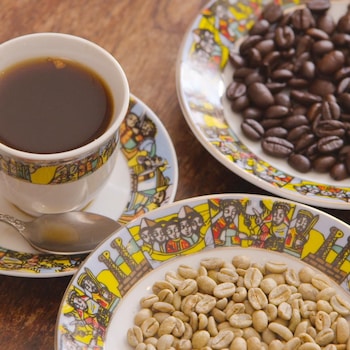Une tasse de café, et des grains de café dans des assiettes.