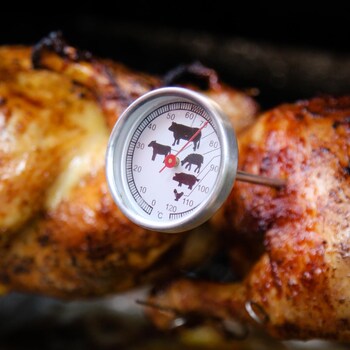 Un thermomètre à viande piqué dans du poulet.