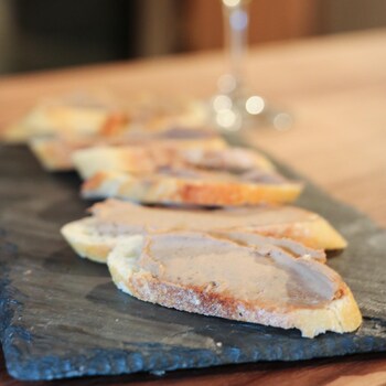 Des tranches de pain garnies de mousse de foie de volaille, déposées sur une ardoise. 