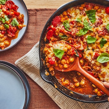 Poêlon en fonte plein de tomates, de pois chiches et de fromage.