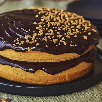 Un gâteau à deux étages, nappé d'un glaçage au chocolat, est sur la table.