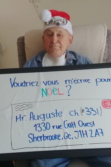 Monsieur Auguste tient un large papier sur lequel est écrit : « voudriez-vous m'écrire pour Noël? »