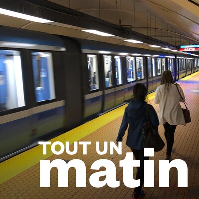 Des gens marchent sur le quai du métro, alors qu'un train passe.
