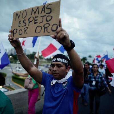 Une personne avec une banderole au milieu d'une manifestation.