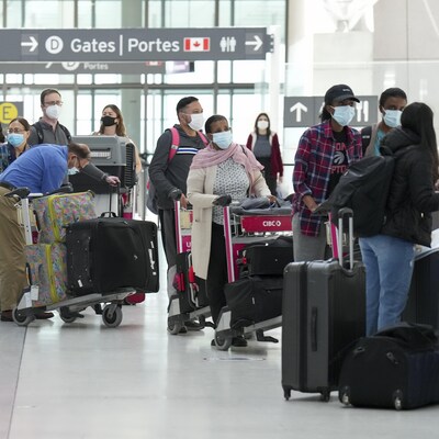 Des personnes font la queue pour s'enregistrer à l'aéroport international Pearson de Toronto.