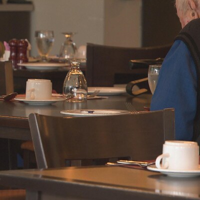 Des aînés assis à des tables dans la salle à manger commune.