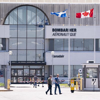 Des employés marchant devant l'édifice de Bombardier aéronautique à Montréal.
