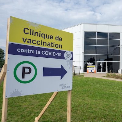 Un panneau devant un bâtiment indique la présence d'une clinique de vaccination.