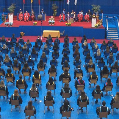 L'ensemble de la salle prise en photo. Les diplômés sont vêtus de leur toge et assis sur des chaises.