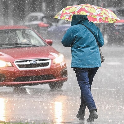 Un piéton marche avec un parapluie. 