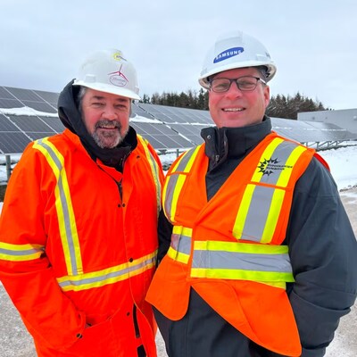 Mike Thususka et Greg Gaudet interviewés devant de grands panneaux solaires à l'extérieur.