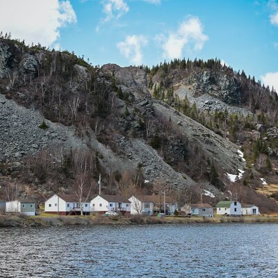 Quelques maisons sur le rivage devant des collines rocheuses.