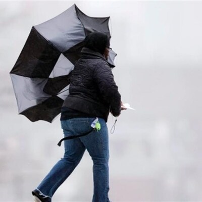 Une femme tient un parapluie retourné par le vent.