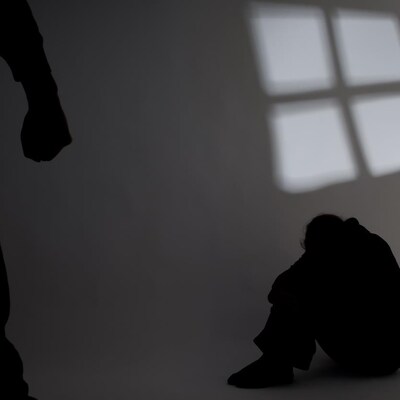 Une personne est assise par terre et une autre personne au premier plan a le poing serré. 