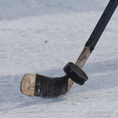 Un bâton de hockey qui frappe une rondelle sur une patinoire.