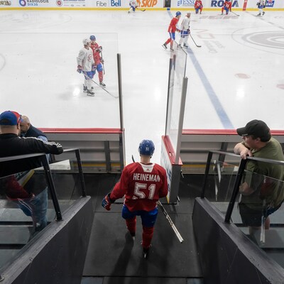 Un joueur de hockey marche vers la porte de la patinoire où se déroule un entraînement de son équipe.