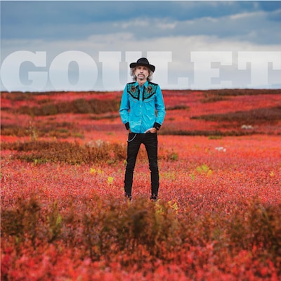 L'auteur-compositeur-interprète Éric Goulet au centre d'un champ de fleurs rouges.