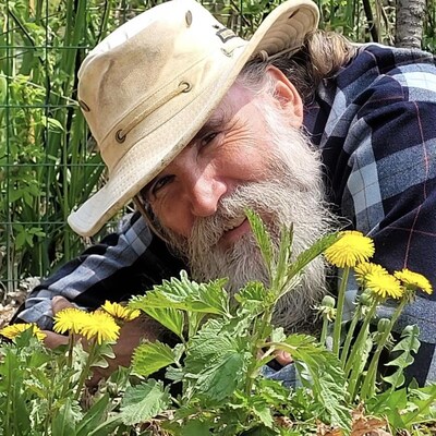 Stefan Dixon allongé sur le sol à côté de pissenlits.