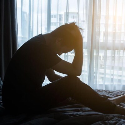 Un homme dans son lit se tient la tête.