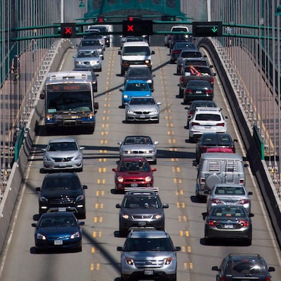 Des voitures, un autobus et des cyclistes traversent un pont.