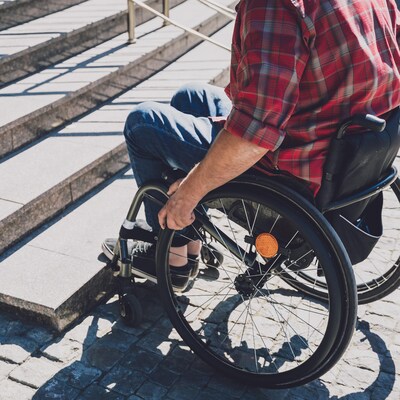 Une personne en fauteuil roulant qui fait face à un escalier.