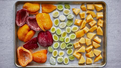 Des poireaux, des poivrons et de la courge, congelés sur une plaque de cuisson. 