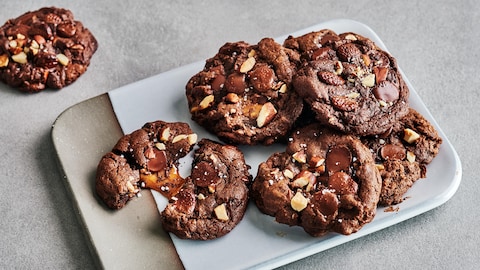 Plusieurs biscuits au chocolat, aux amandes et au caramel dans une assiette.