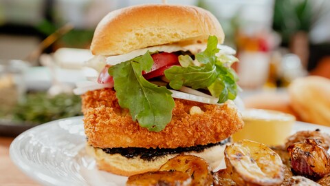 Un burger végétariens de portobello dans une assiette avec des pommes de terre rôties.