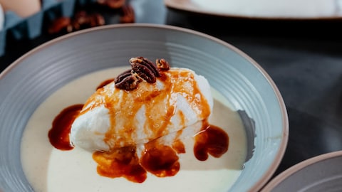 Une île flottante dans de la crème anglaise, nappée de sauce au caramel écossais et garnie de pacanes.