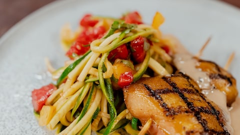 Une assiette de poulet grillé cari et soya avec linguine de courgettes.
