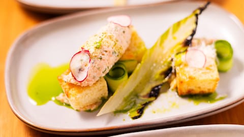 De la rillette de saumon dans une assiette avec des croûtons, des légumes croquants et une vinaigrette aux herbes.
